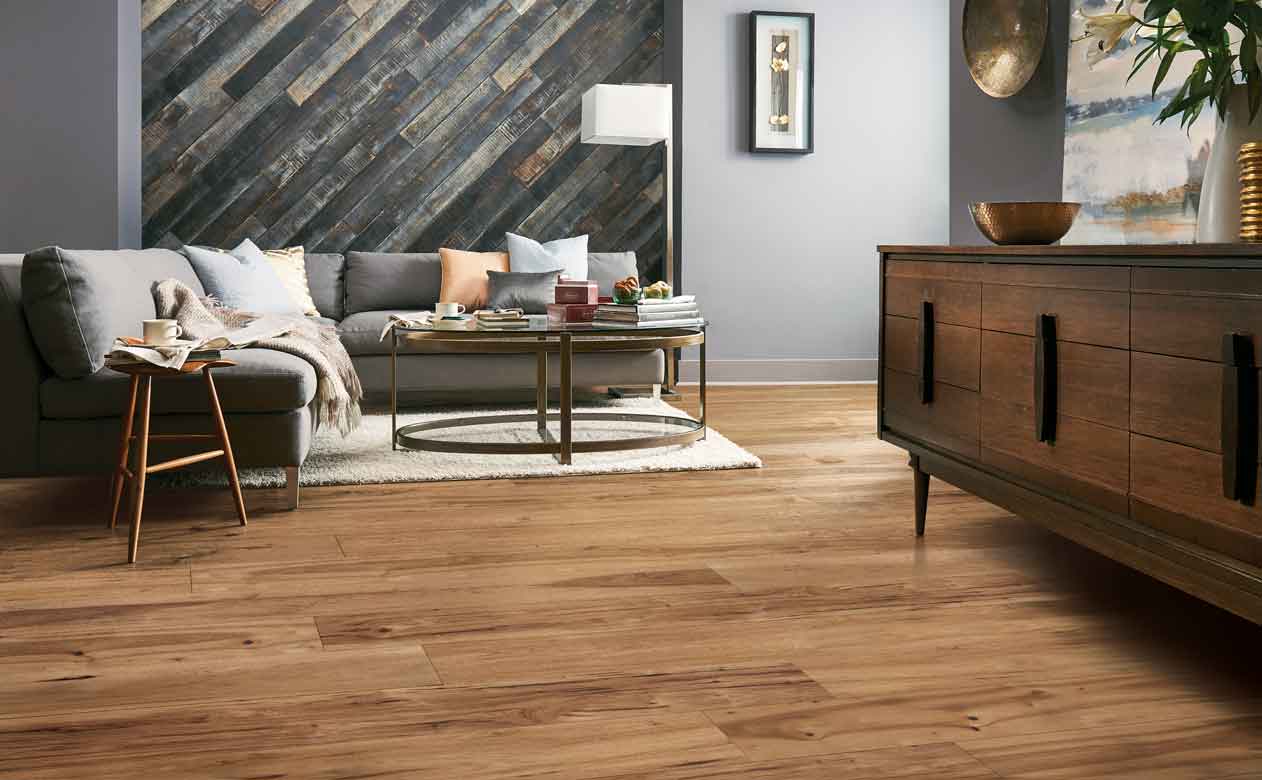 Hardwood flooring with grey couch and brown cabinet. 